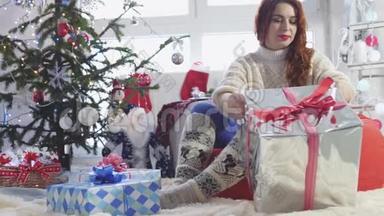 年轻漂亮的红发女人在圣诞树旁打开一个<strong>礼品</strong>盒。 慢动作。 3840x2160
